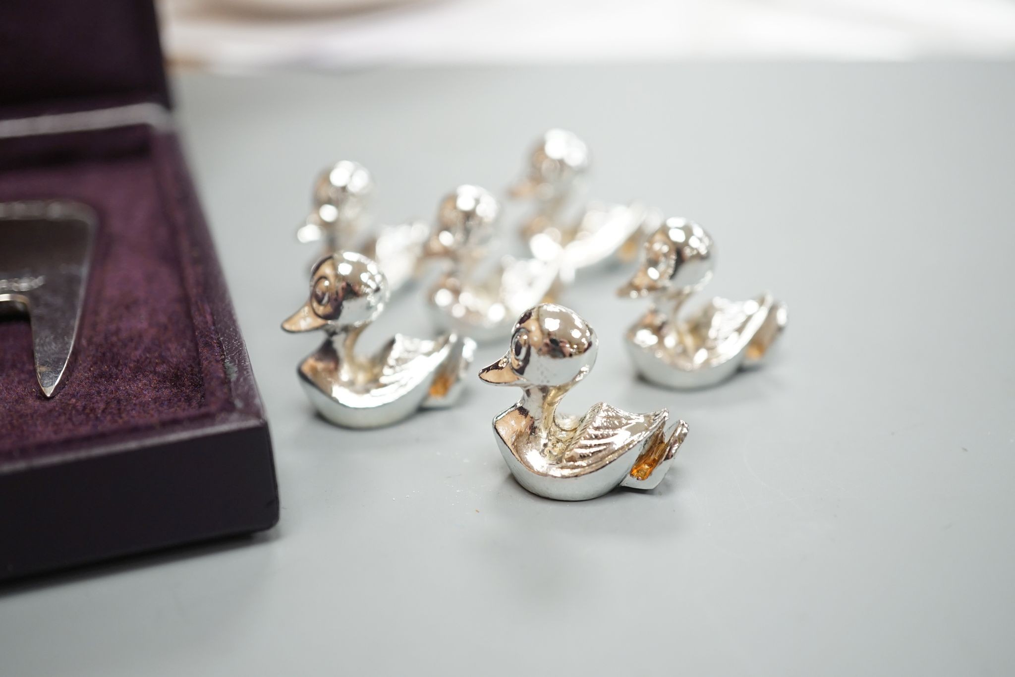 A modern Asprey cased silver golfer's companion set, comprising a tee, marker and pitch mark repairer, together with a set of six metal duck menu holders.